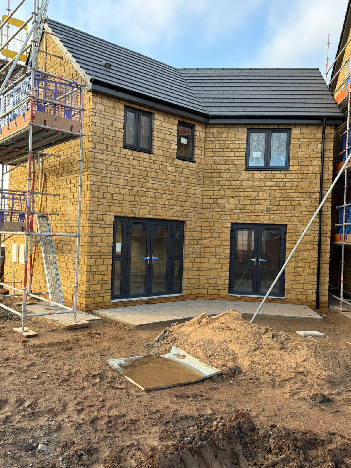New build stone house under construction with scaffolding by Derby Brickwork Ltd